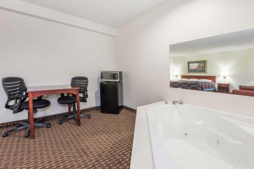 ein Bad mit einer Badewanne, einem Schreibtisch und einem Bett in der Unterkunft Super 8 by Wyndham Gardner in Gardner