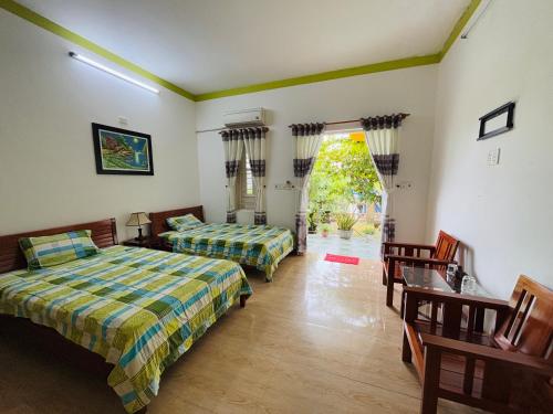 1 Schlafzimmer mit 2 Betten und einer Tür zum Hof in der Unterkunft De Vong Riverside Homestay in Hoi An