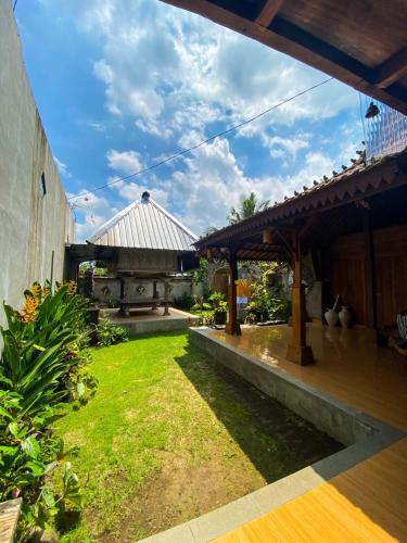a garden with a patio and a house at Joglo Breeze Guesthouse and Villa in Tabanan
