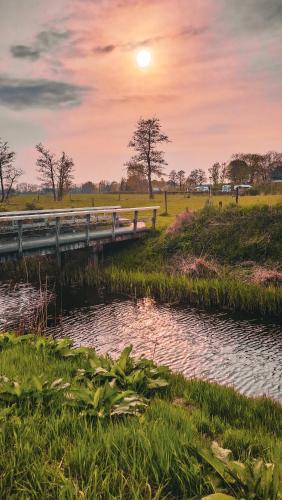 a bridge over a river with the sunset in the background at Herberg Het Rechthuis in Rinsumageest