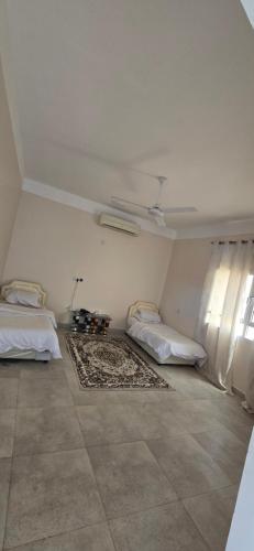 a white room with two beds and a window at Sunset view hill jabal shams in Misfāh