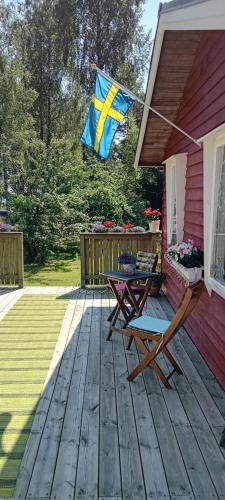 Una bandera en una terraza con una mesa de picnic en una casa. en Strandvikstugan, en Väse