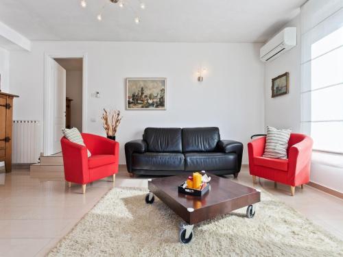 a living room with a black couch and two red chairs at Sunny Villa with Terrace in Comerio
