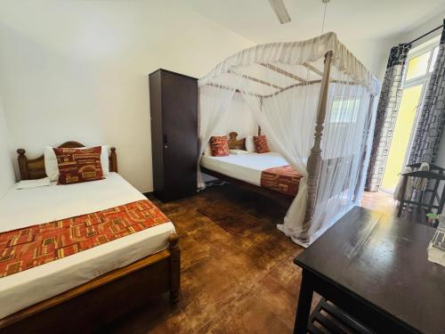 a bedroom with two beds and a canopy bed at Nooit Gedacht Holiday Resort Unawatuna in Unawatuna