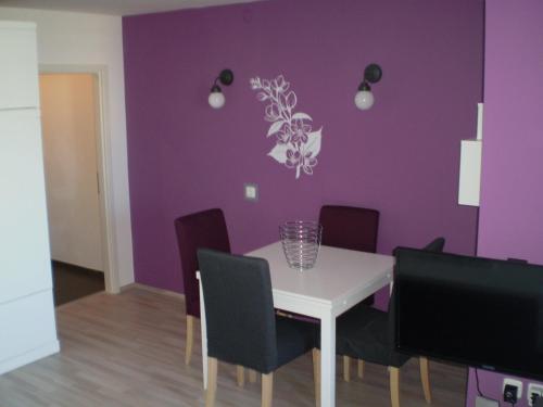 ein Esszimmer mit lila Wänden, einem weißen Tisch und Stühlen in der Unterkunft Ferienwohnung Marinablick in Wendtorf