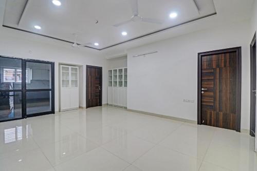 une grande pièce vide aux murs blancs et aux portes en bois dans l'établissement Super TOWNHOUSE JAHNAVI GROUP BESIDES NEXUS MALL, à Hyderabad
