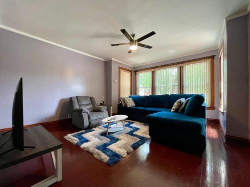 a living room with a blue couch and a ceiling fan at Fully Furnished 2BR Apartment Near Oak Park I Utilities Included I Car Rental Available in Chicago