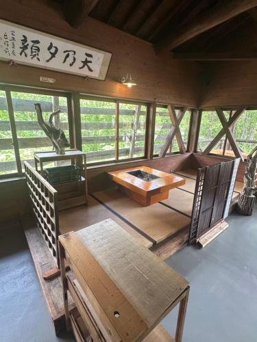 a room with a table and a bench and windows at Yamanomura Campsite in Hida