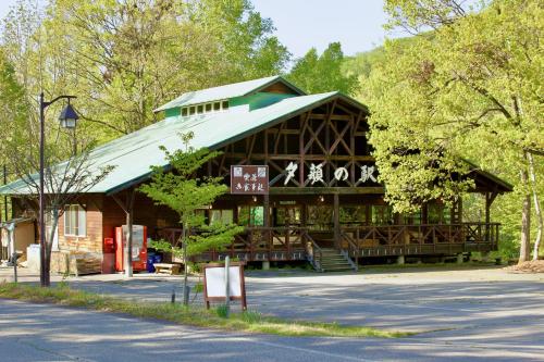 a large wooden building with a green roof at Yamanomura Campsite in Hida