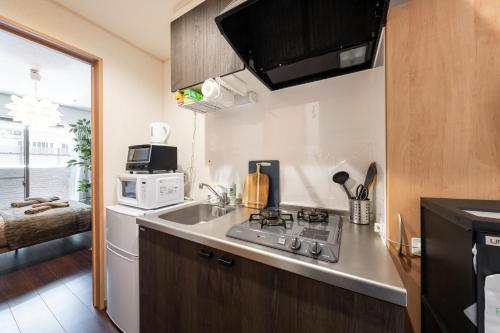 a small kitchen with a sink and a microwave at Oasis Stay Tokyo in Soka