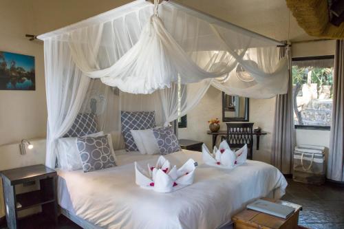 a bedroom with two beds with white drapes at Ezulwini Game Lodges in Balule Game Reserve