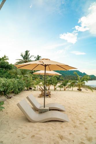 a beach with an umbrella and chairs on the sand at Bamboo Surf Beach in San Isidro