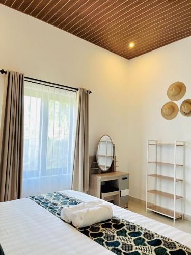 a bedroom with a bed and a mirror and a window at The Res Village Lombok in Kuta Lombok