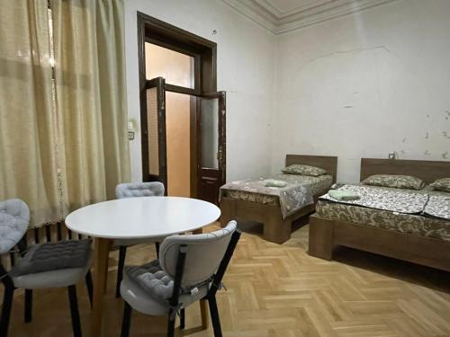 a room with two beds and a table and chairs at Central House in Kutaisi