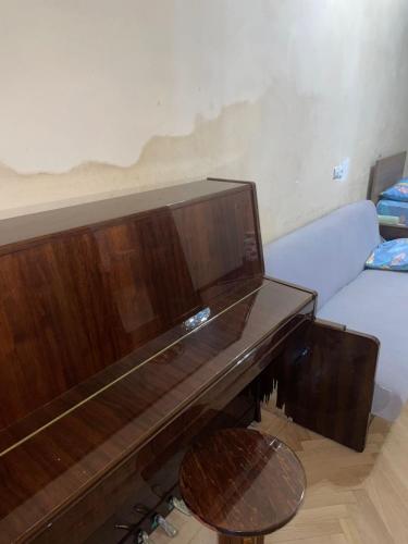 a wooden piano in a living room with a couch at Central House in Kutaisi