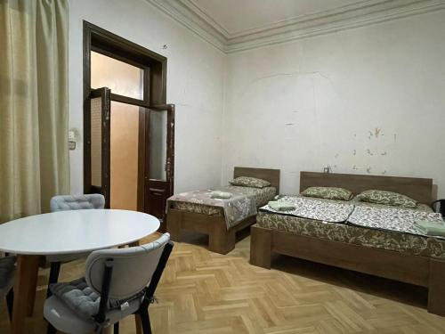 a room with two beds and a table and chairs at Central House in Kutaisi