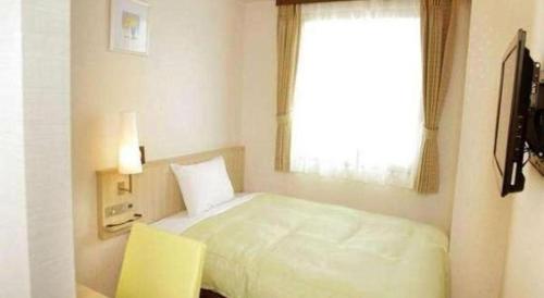 a small bedroom with a bed and a window at Hotel Naito Kofu Showa in Kofu