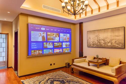 a living room with a large screen tv on the wall at 北京一瓢客栈 Beijing YiPiao Inn in Beijing
