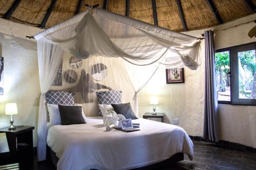 a bedroom with a white bed with a canopy at Ezulwini Game Lodges in Balule Game Reserve