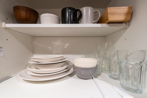 a pile of plates and bowls on a shelf at Oasis Stay Tokyo in Soka
