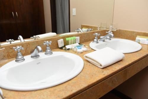 a bathroom counter with two sinks and a mirror at Hotel y Casino Del Río - Las Grutas in Las Grutas