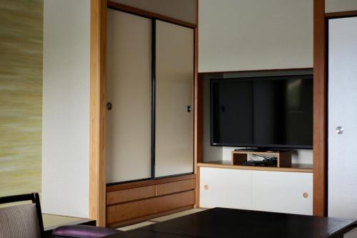 a living room with a tv and a sliding glass door at Sun Urashima Yuki no Sato in Toba