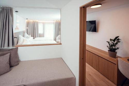 a bedroom with a mirror next to a bed at Ganischgerhof Mountain Resort & Spa in Nova Ponente