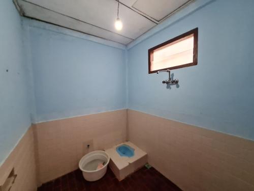 a bathroom with a toilet and a window and a sink at Abadi Guest House Tuktuk in Tuk Tuk