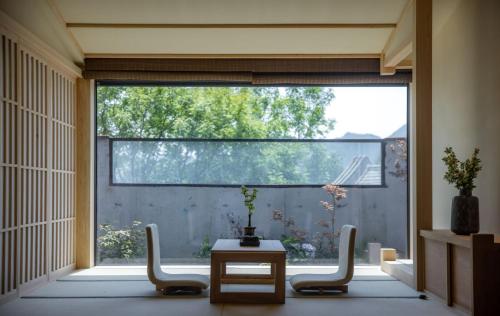 a room with a large window with chairs and a table at 北京一瓢客栈 Beijing YiPiao Inn in Beijing