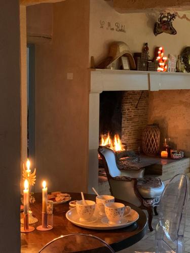 a table with plates and candles and a fireplace at Le Mas Bastide in Gaudonville