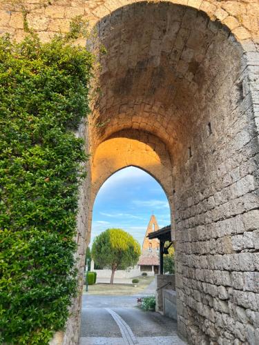 an archway in a brick wall with a building in the background at Le Mas Bastide in Gaudonville