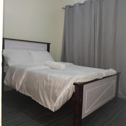a bed with white sheets and pillows in a bedroom at Evin apartment in Gilgil