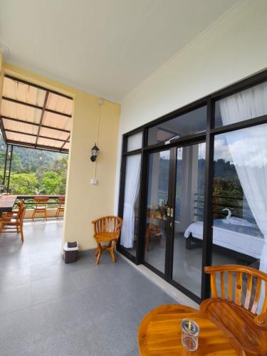 a room with a balcony with a bed and windows at Laras Homestay Munduk in Munduk