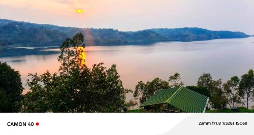 a view of a lake with a house and a rainbow at Inzozi Eco Camp in Gishyita