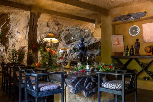 a dining room with a table and chairs and a stone wall at Ezulwini Game Lodges in Balule Game Reserve