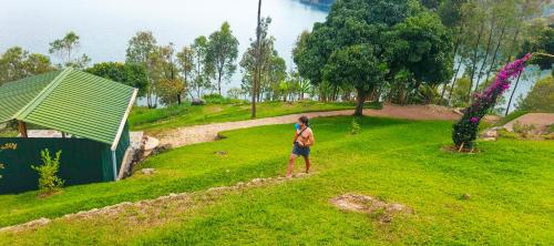a person standing on a grassy hill next to a building at Inzozi Eco Camp in Gishyita