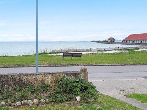 a bench sitting on the side of a road near the ocean at Seaside Retreat in Bandholm-By Traum in Bandholm