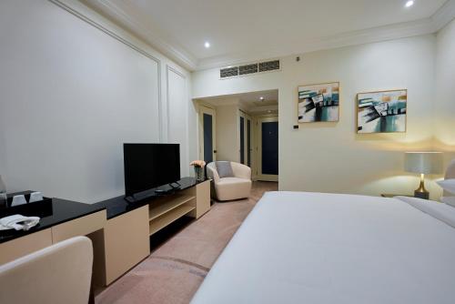 a hotel room with a bed and a tv at Grand Regency Doha, Trademark Collection by Wyndham in Doha