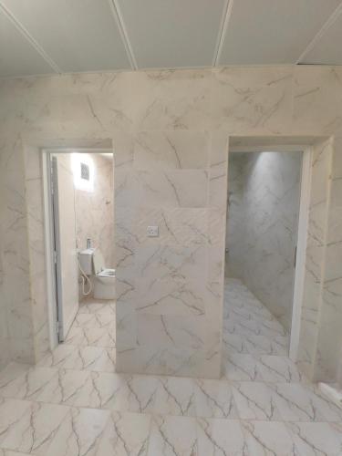 Majrá al GhāfにあるAlwahyada chaletのトイレと鏡を備えた白い大理石のバスルーム