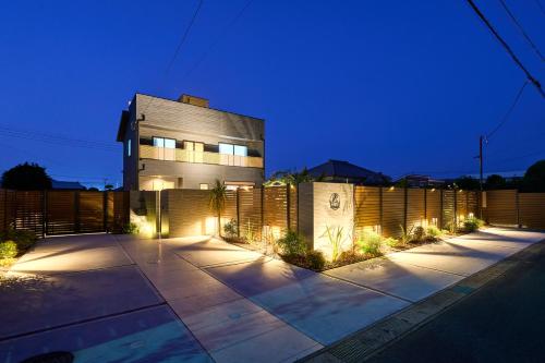 a house with lights in front of a fence at Color Bee Villa 99 海の見える貸別荘,プライベートプール, サウナ, ジャグチ,ドッグラン,BBQ付き in Shirako
