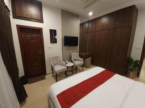 a hotel room with a bed and two chairs at Aspire Lodge, G11 Islamabad - A Family Guest House & Hotel in Islamabad