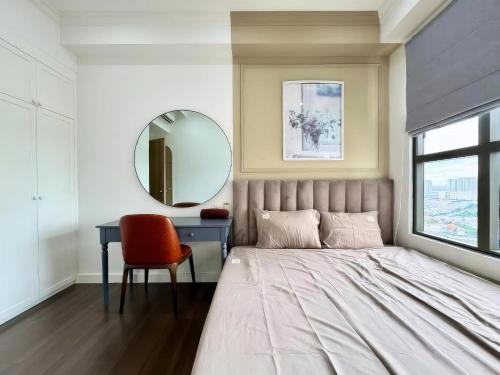 a bedroom with a bed and a mirror and a chair at The Sun Avenue Apartment Moonlight in Ho Chi Minh City