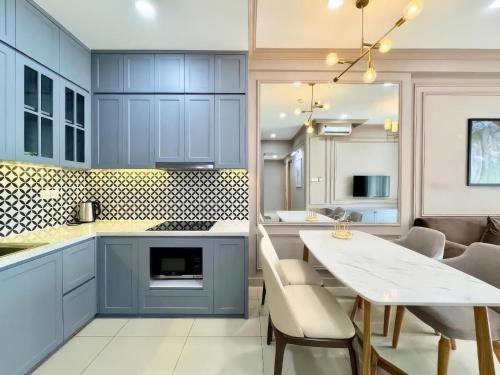 a kitchen with blue cabinets and a white table at The Sun Avenue Apartment Moonlight in Ho Chi Minh City