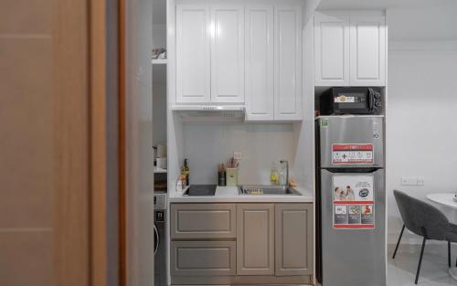 a small kitchen with white cabinets and a refrigerator at The Sun Avenue Apartment Moonlight in Ho Chi Minh City