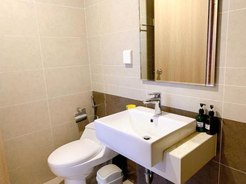 a bathroom with a white sink and a toilet at The Sun Avenue Apartment Moonlight in Ho Chi Minh City
