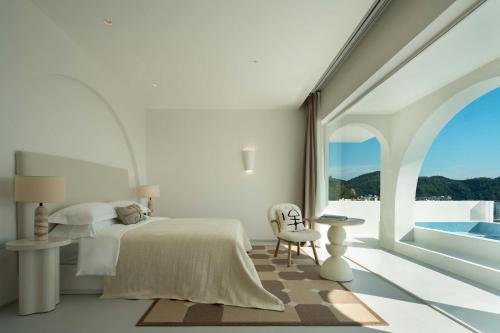 a white bedroom with a bed and a large window at Miyue Shenzhen Blue and White Holy Island Cliff Pool Hotel in Shenzhen