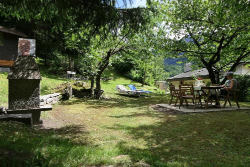 a woman sitting at a table in a yard at Casa Da Tos - appartamento per 5 persone in Lavorgo