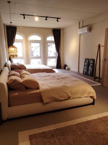 a large bedroom with a large bed with windows at Mokū Georgetown Pre-war House 4BR 5-14pax in George Town