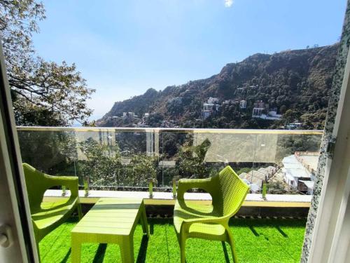 a balcony with a table and chairs and a view of a mountain at The Boho Mussoorie in Mussoorie