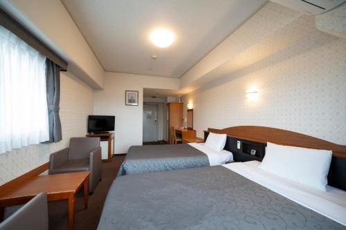 a hotel room with two beds and a television at Castle Inn Komaki in Komaki